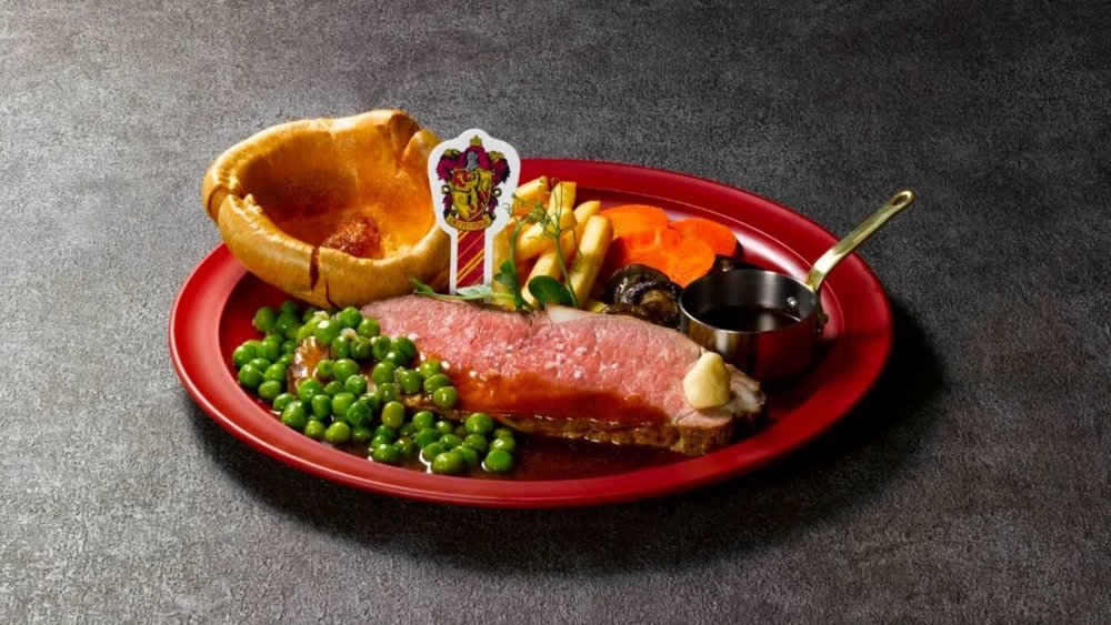 Roast beef, peas, caarrots, fries, bread, and sauce on a red plate