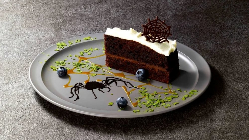 slice of chocolate mousse cake with spider-themed decorations on a grey plate