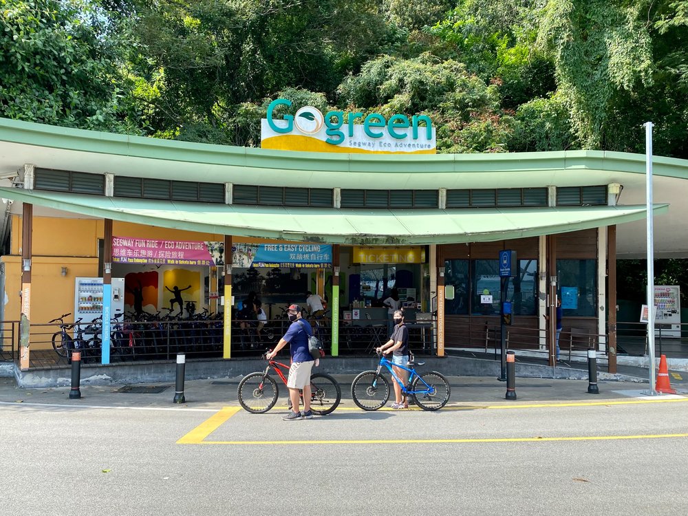 two people riding bikes in front of Go Green logo