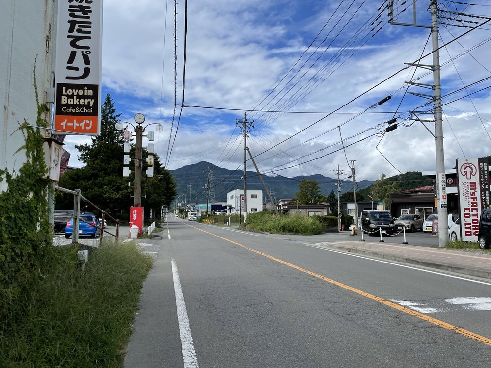 a wide road with clear blue skies and Japanese signage