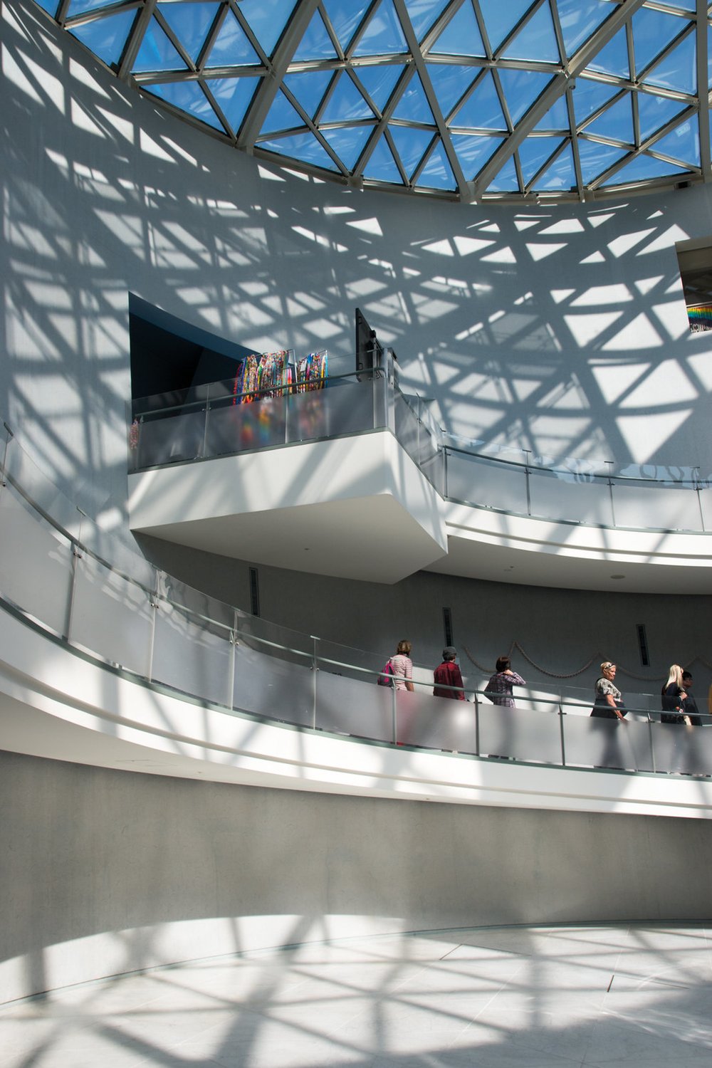 People walking inside a museum with an open ceiling