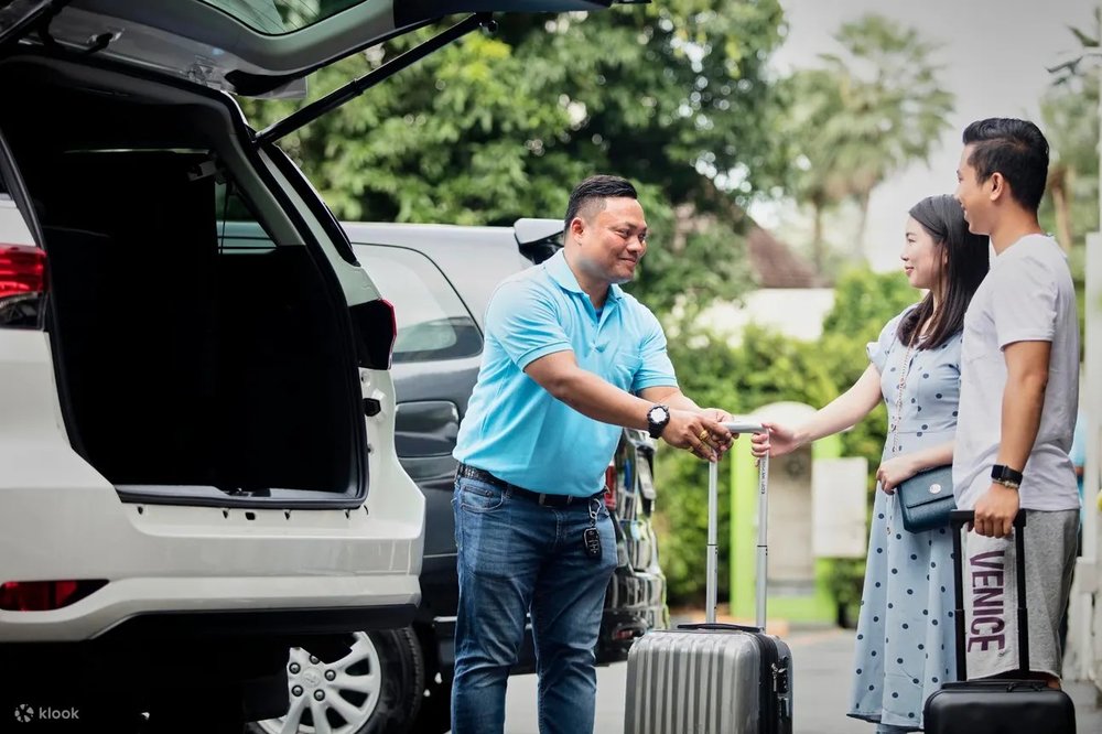 Driver assisting man and woman with their luggages