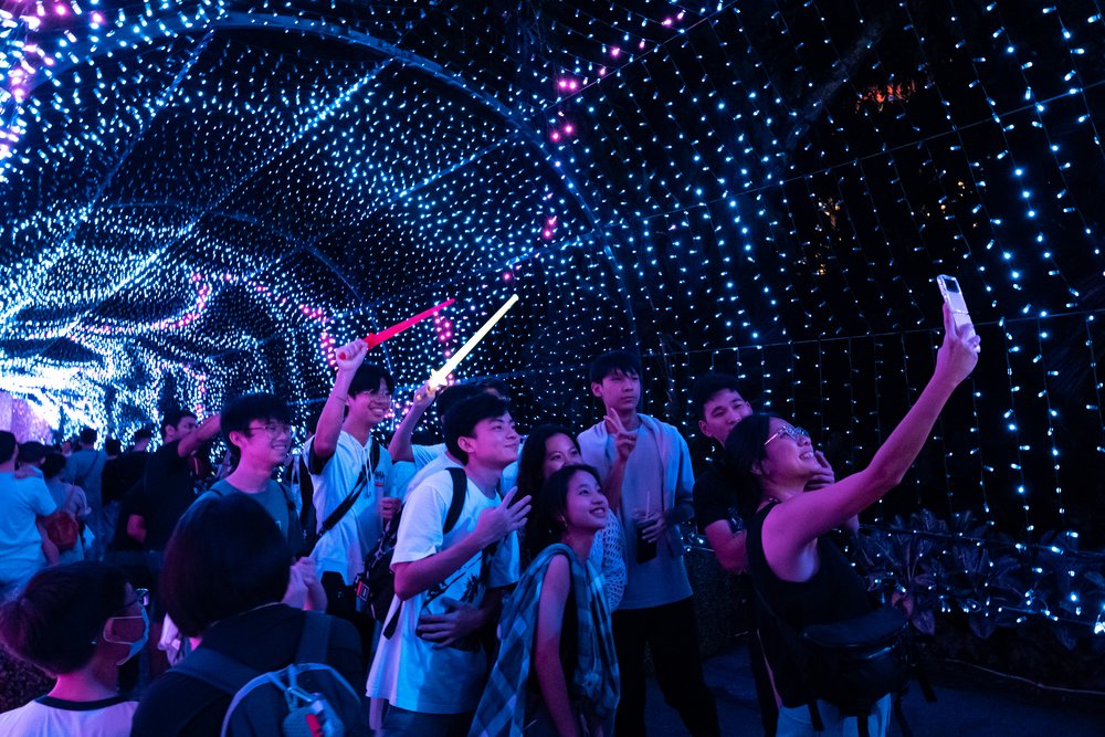 people taking photos under an arc of christmas lights