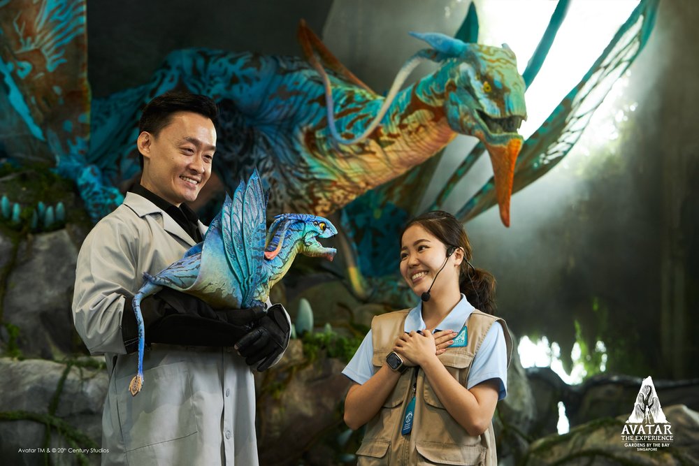 Man handling a creature from Avatar while woman looks in wonder