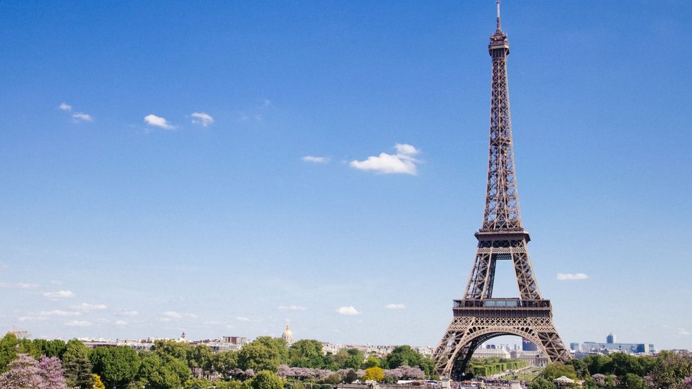 the eiffel tower in paris stands tall with clear blue skies in the background