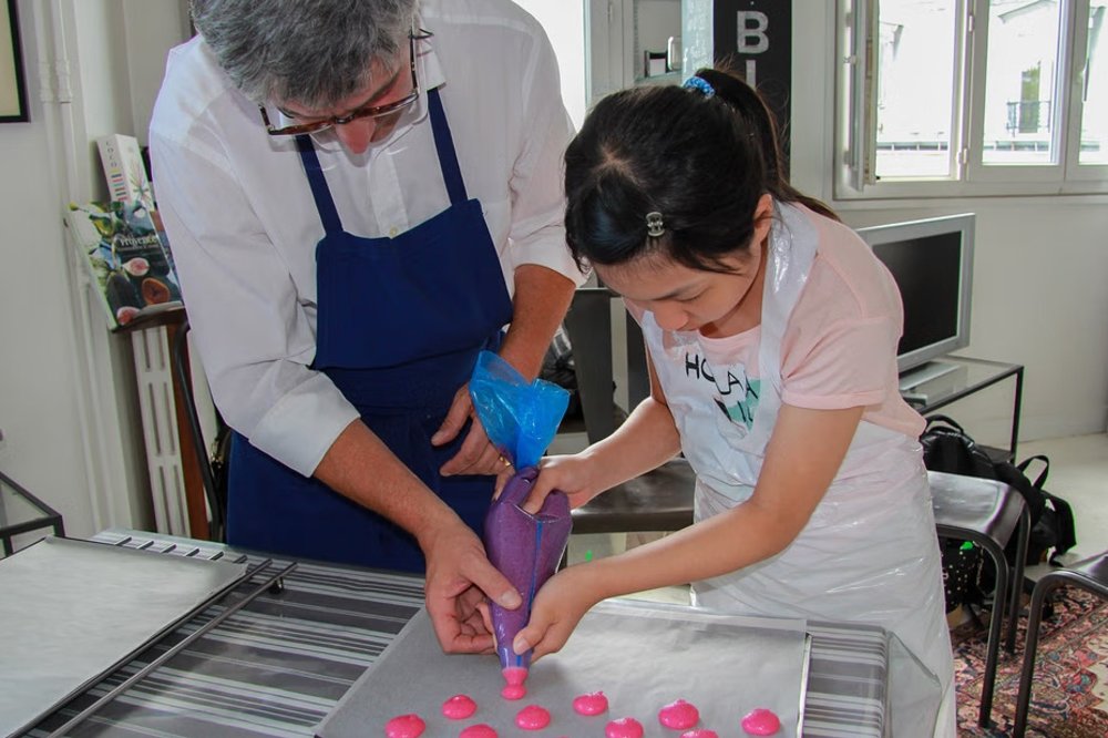adult teaching child how to make macarons