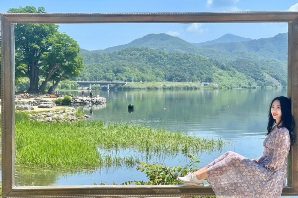 a woman posing in a frame-like structure overlooking a lake in Dumulmeori