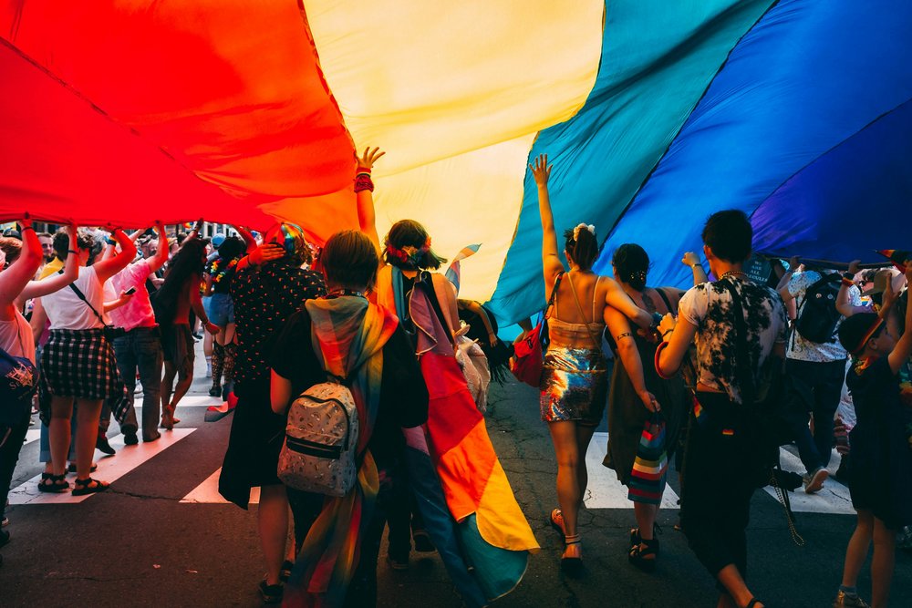 Group of people under the LGBTQIA flag