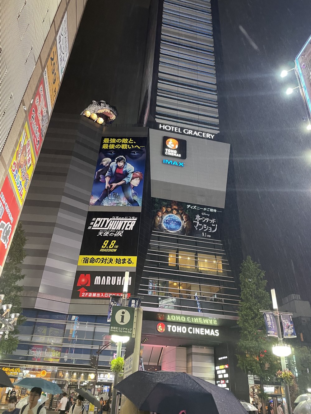 a large godzilla statue stands behind a hotel in tokyo