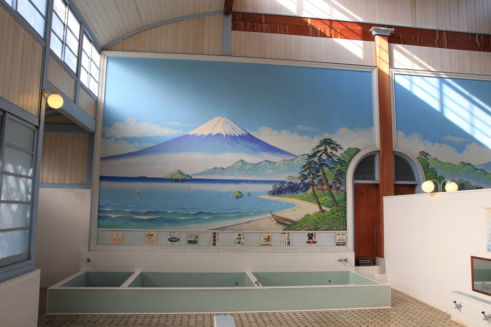 inside an onsen in tokyo with a large painting of mt fuji