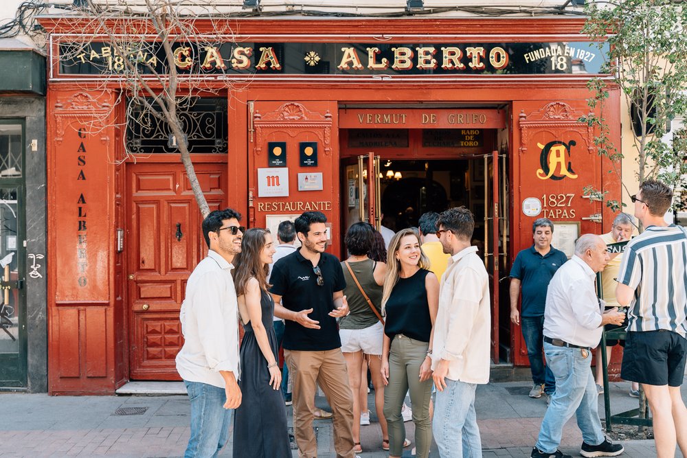 a group of people talking in front of a tapas restaurant