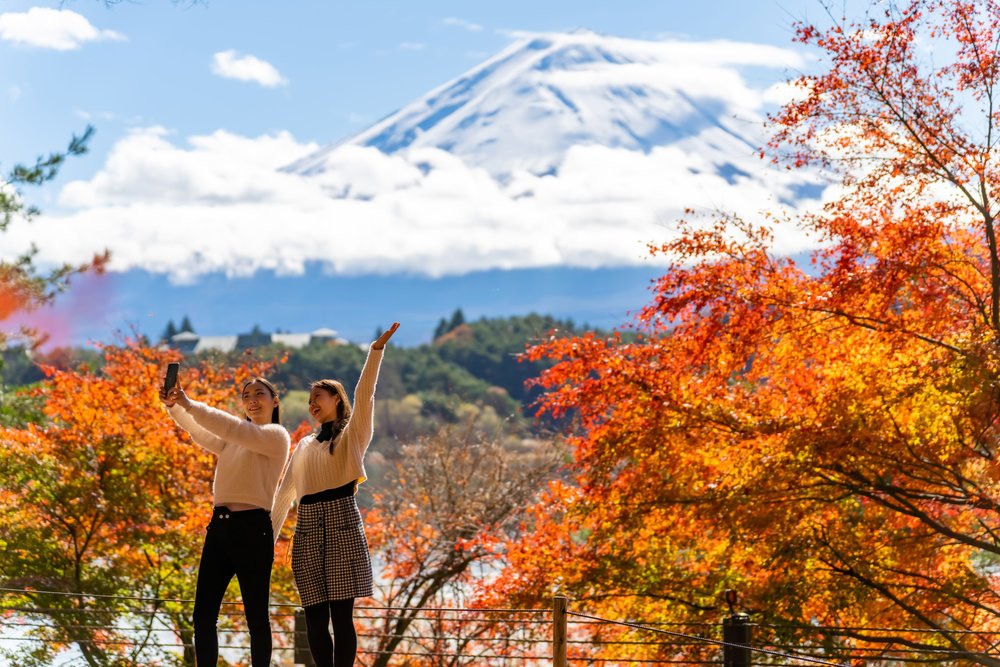 Asian Women Take Photos in front of Fuji in Autumn