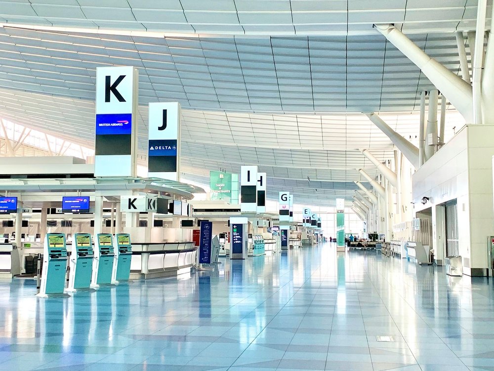 A wide shot of inside Haneda Airport terminal, featuring check-in counters and self-service kiosks