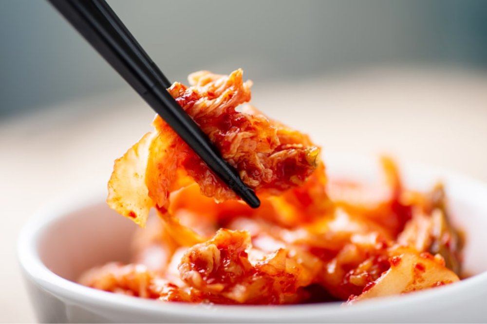 how to make kimchi - chopstick holding a piece of kimchi