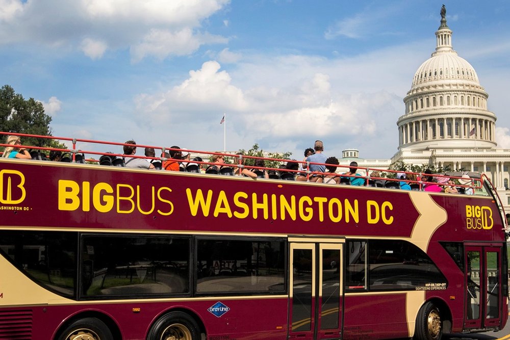 double decker bus with people looking at a white building