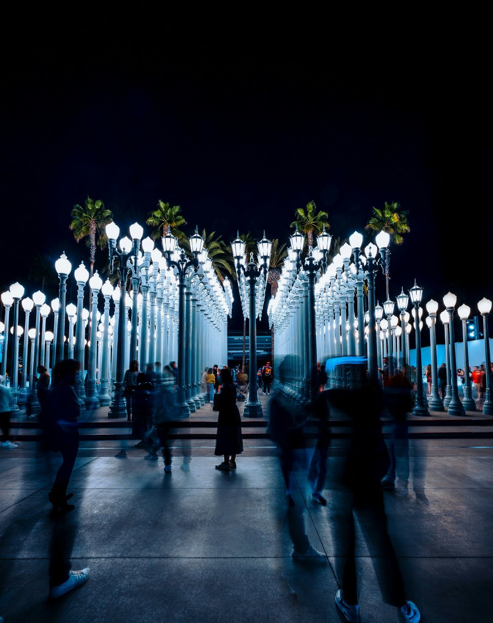 people around tall white streetlamps at night