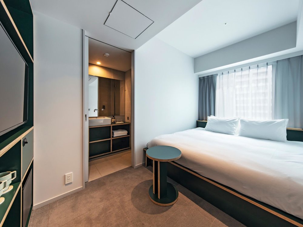 partial view of a hotel room with white bed and green and wooden accents