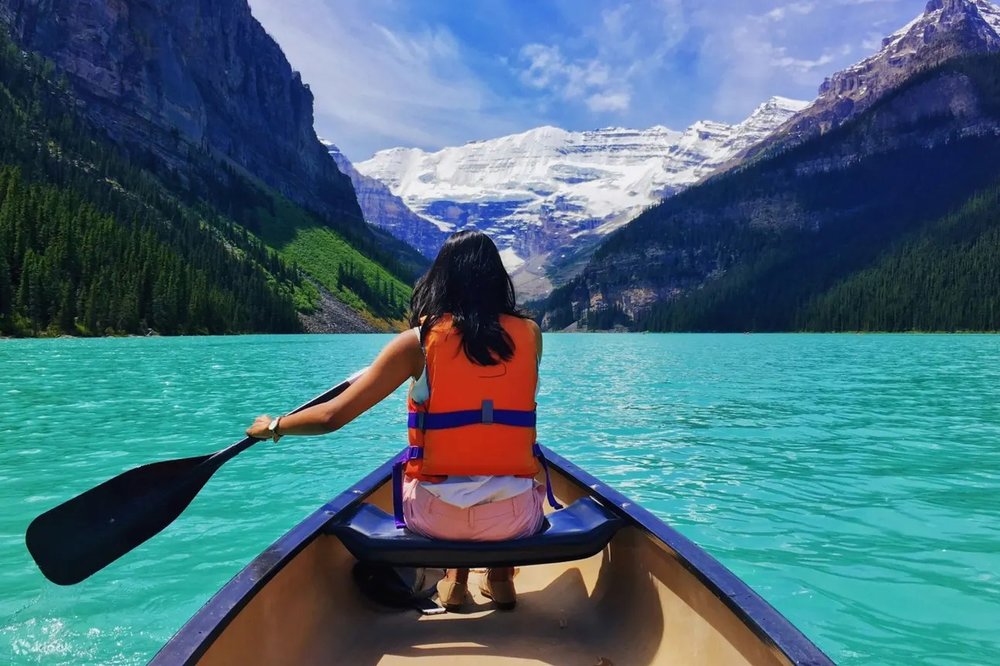 Girl in a boat and paddling across Lake Louise