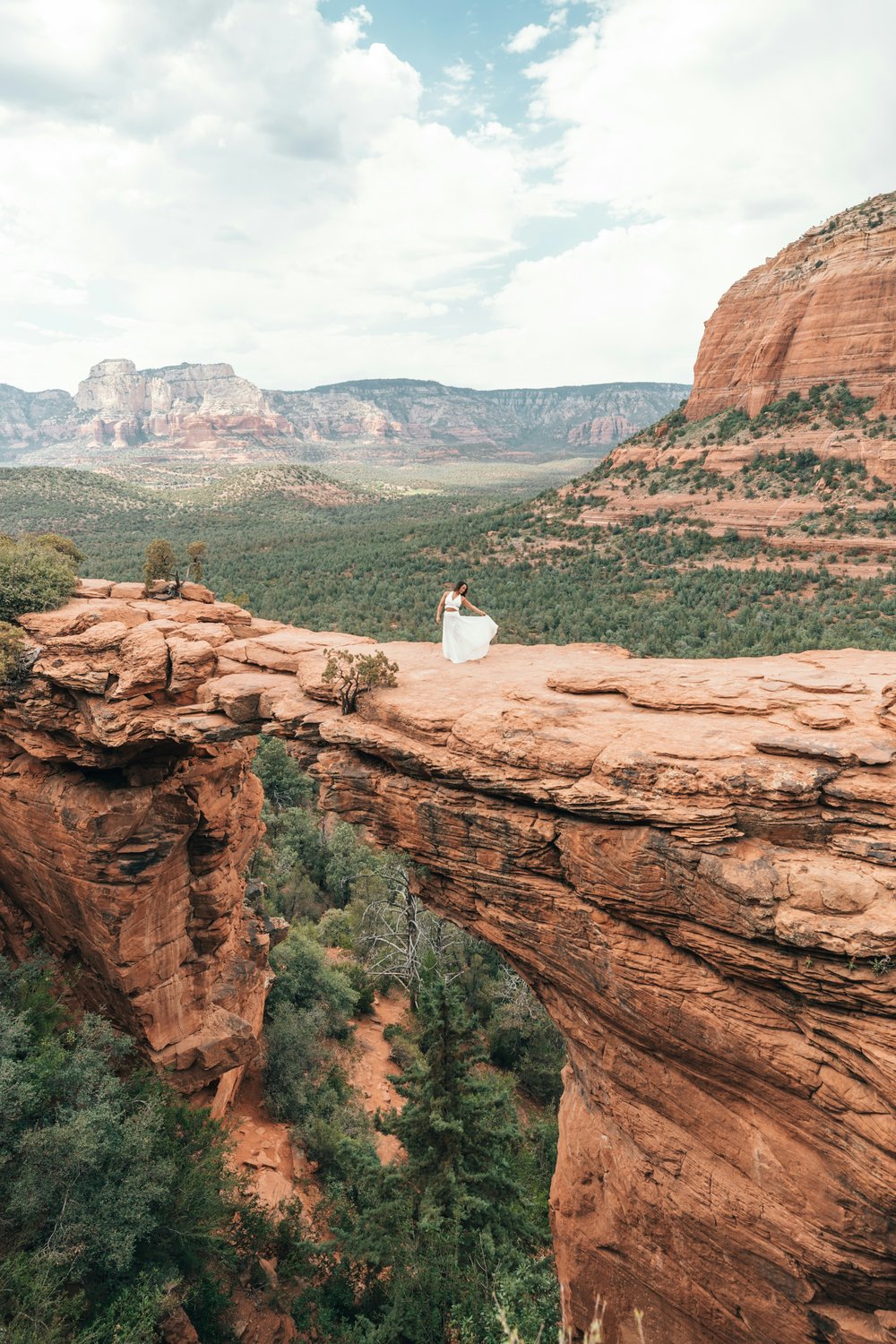 A girl wearing a white gown on top of a cliff