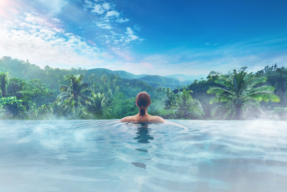 junglia okinawa - woman in infinity pool overlooking a forest