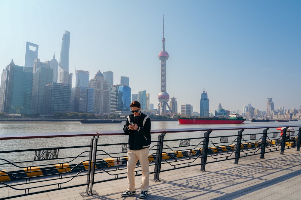 Essential Apps for China Travel - Tourist Using Phone at The Bund in Shanghai