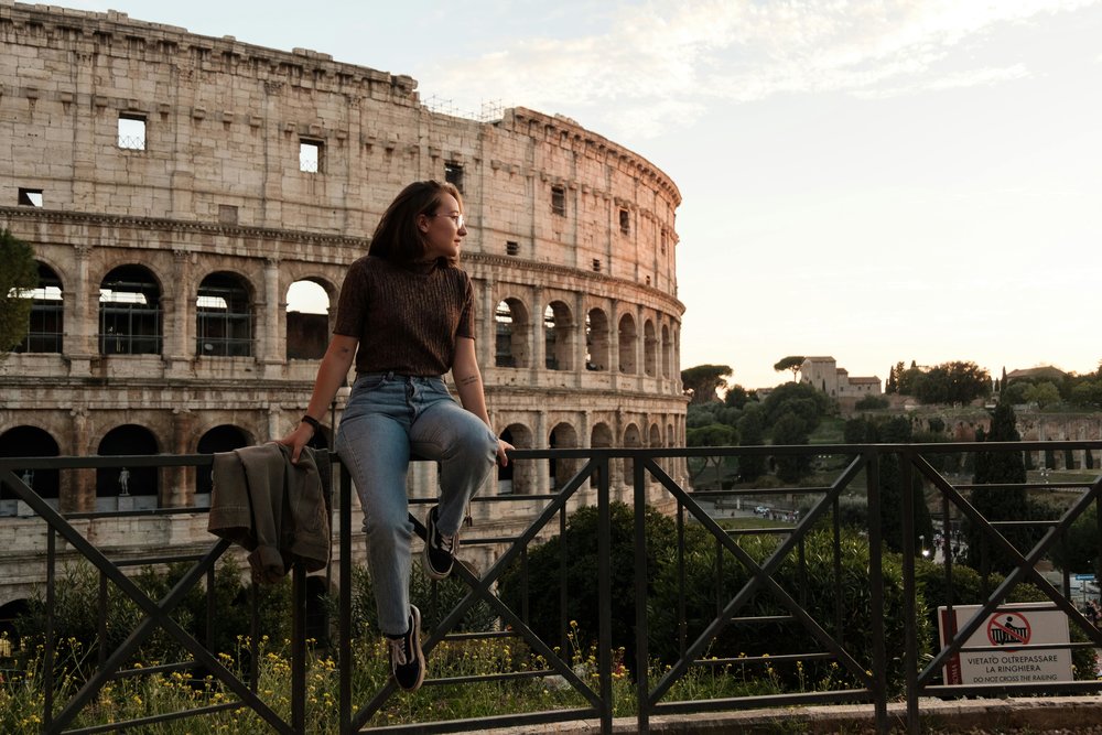 girl leaning against a rail with the colosseum behind her