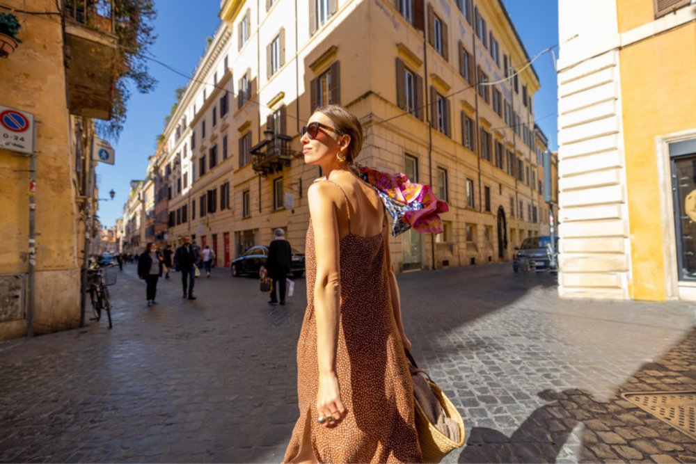 Woman in a brown flowy dress walking on the cozy streets of old town Rome, Italy