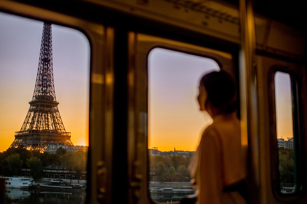 girl looking out a window to eiffel tower