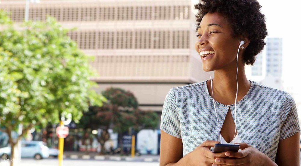woman smiling and on her earphones outdoors