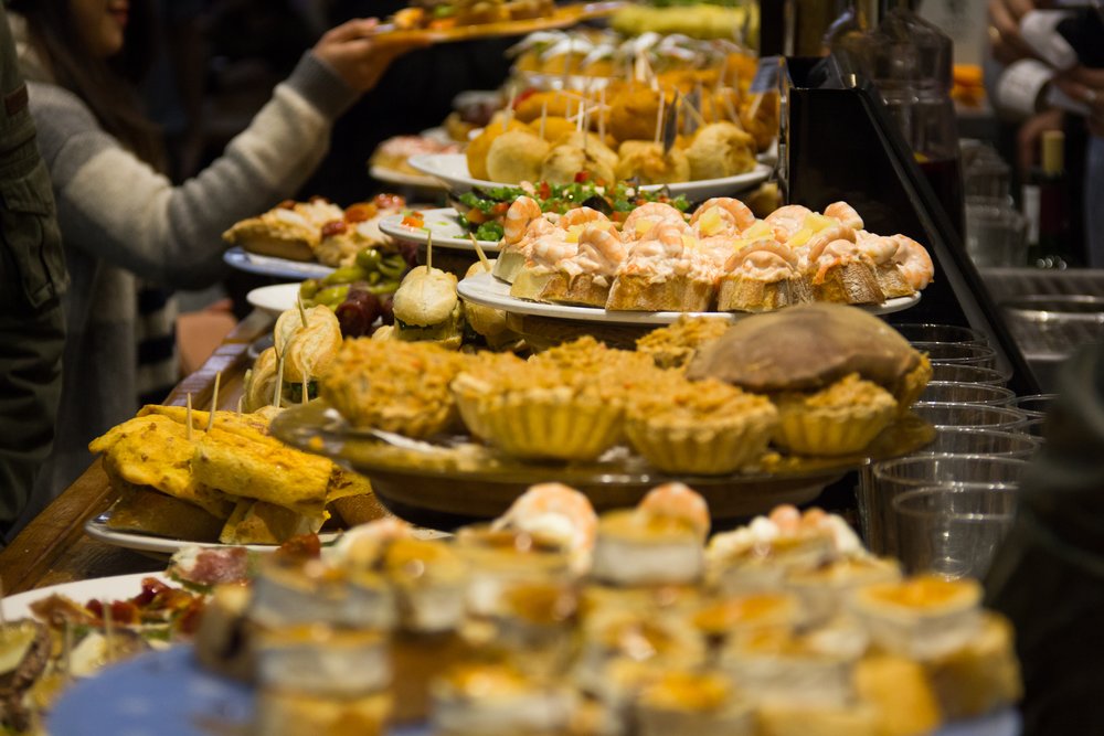 Assorted tapas in Barcelona with shrimp-topped bread, Spanish tortilla, and savory pastries on display