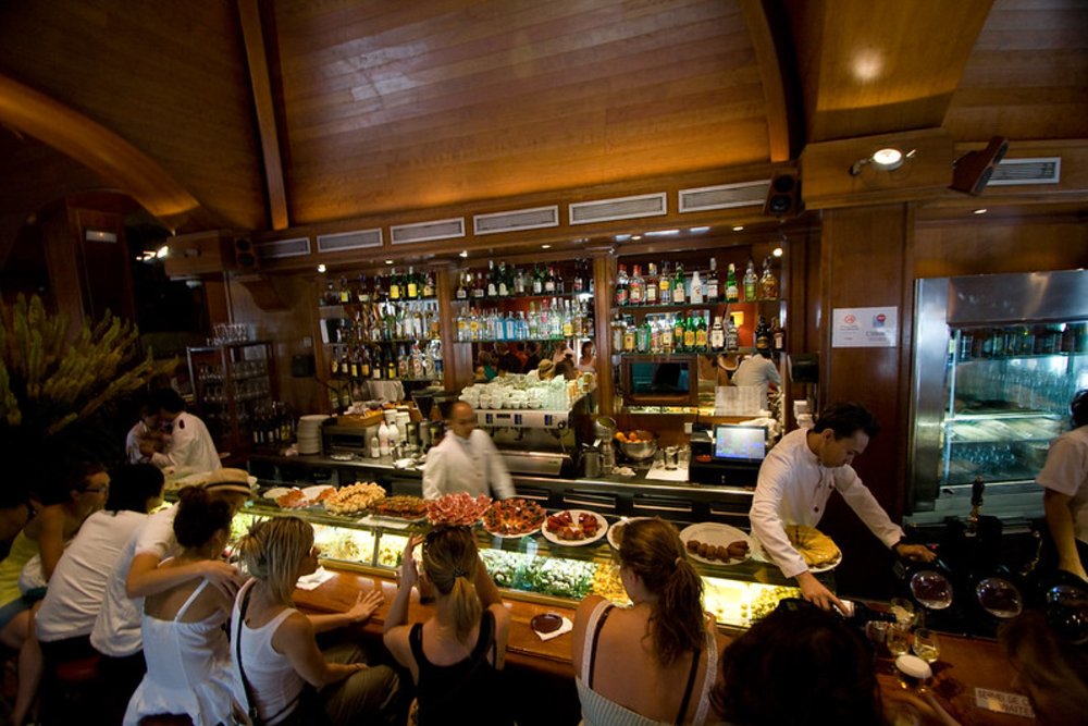 Tapas restaurant in Barcelona with a busy bar counter, diners, and chefs