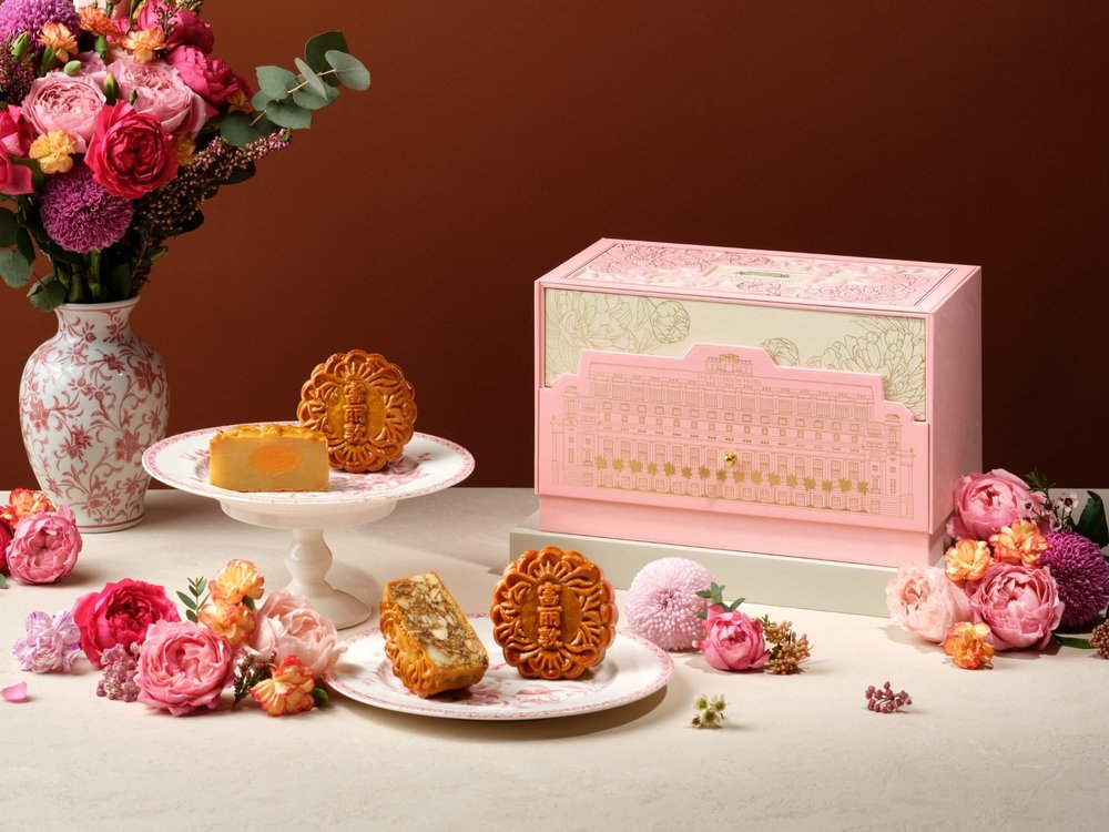 baked mooncakes against brown background with florals and pink gift box
