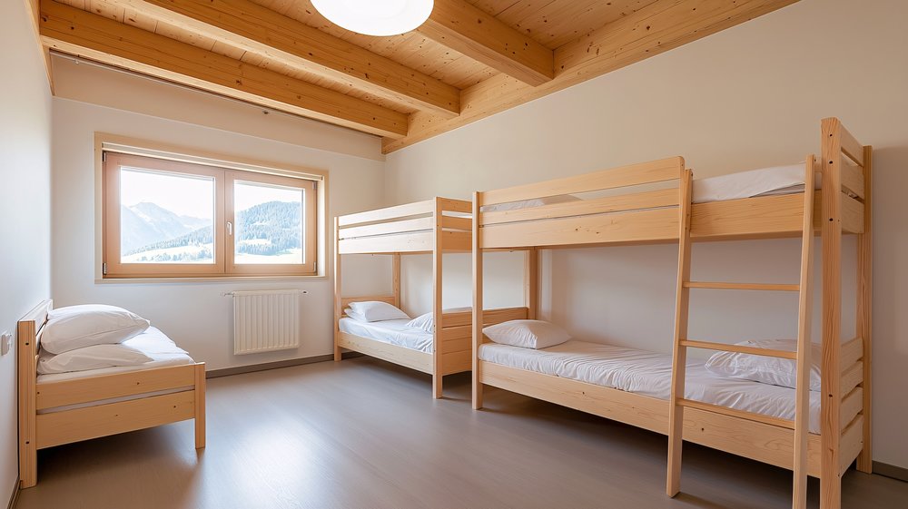 ห้องพักโฮสเทลสไตล์โมเดิร์นสะอาดตา มีเตียงสองชั้น และหน้าต่างวิวภูเขา