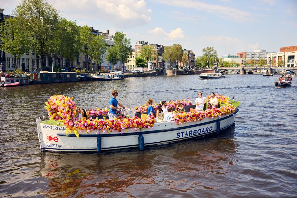 Colorful flower boat canal cruise sailing through Amstel River