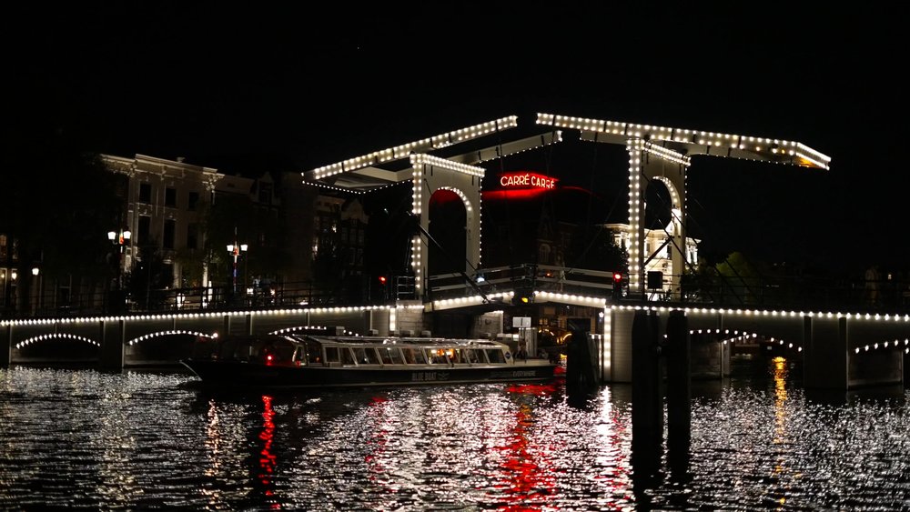 Amsterdam’s Skinny Bridge glowing at night during an evening canal cruise