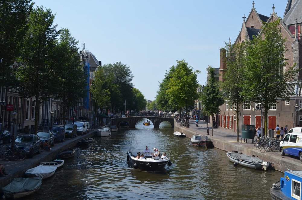 Boats cruising along Amsterdam’s historic canals on a sunny day