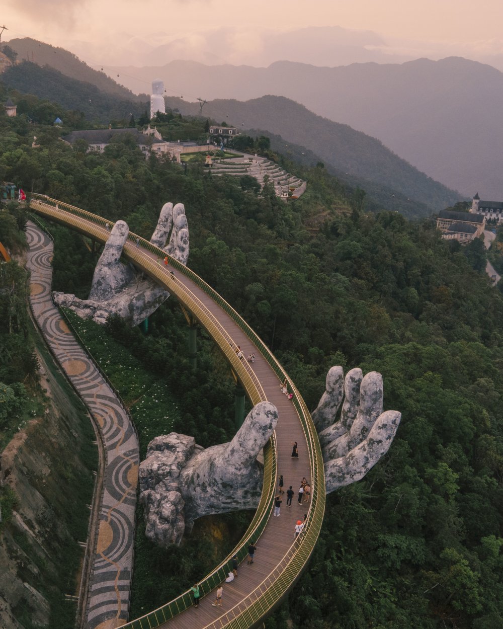 Aerial view of Golden Bridge Vietnam at sunset with forest and mountain backdrop