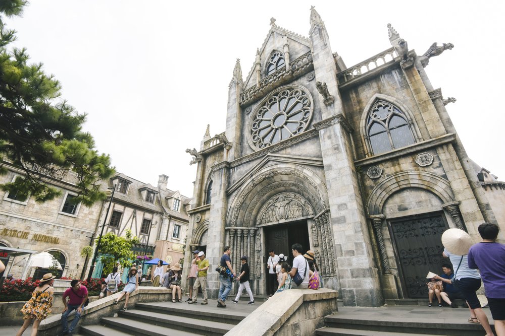 Tourists exploring French-style cathedral architecture at Ba Na Hills French Village in Vietnam