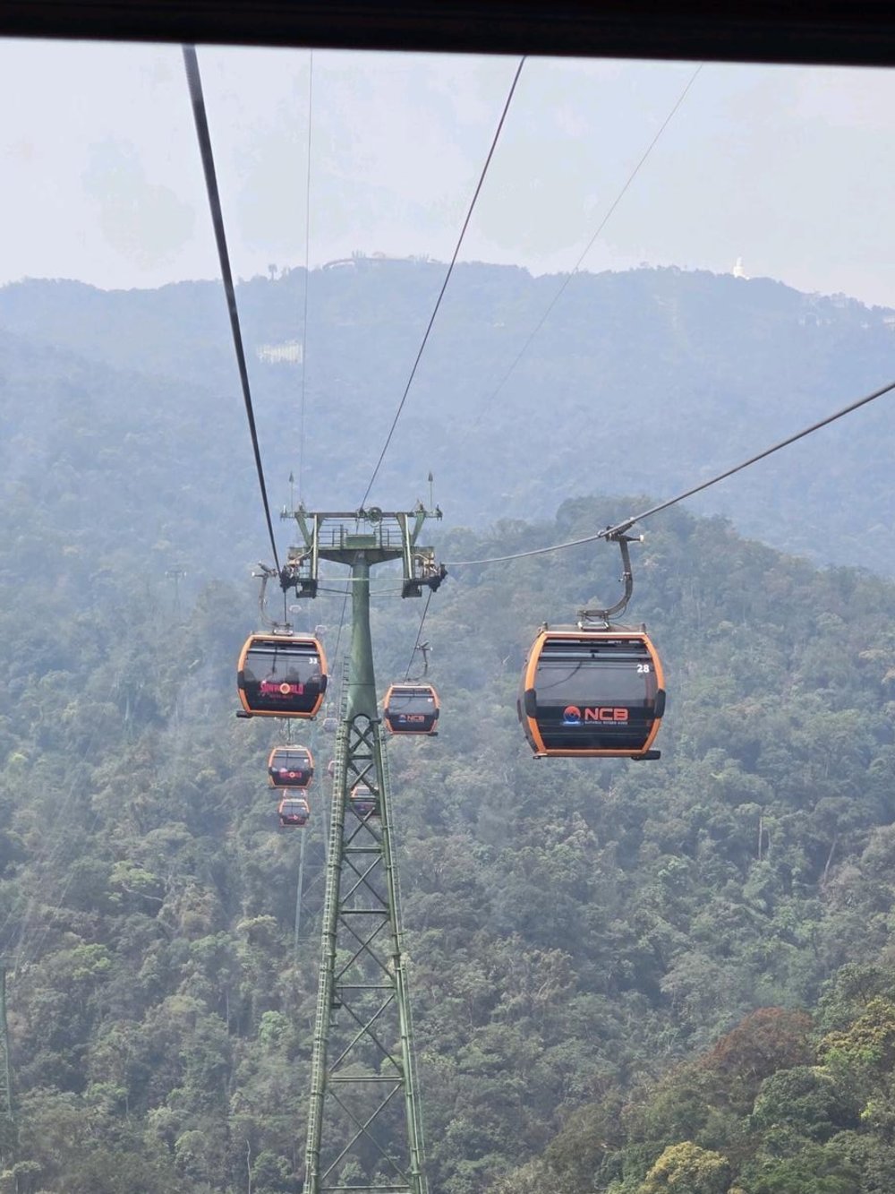 Cable cars traveling through the forested mountains of Ba Na Hills in Da Nang Vietnam