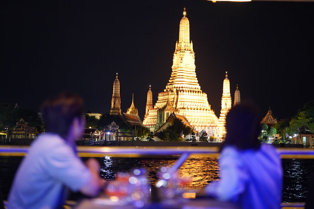 Two people looking at Wat Arun from the cruise