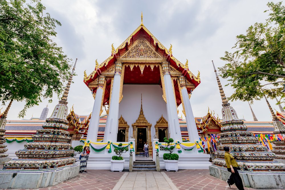 Front view of Wat Pho temple entrance with surrounding chedis and visitors outside