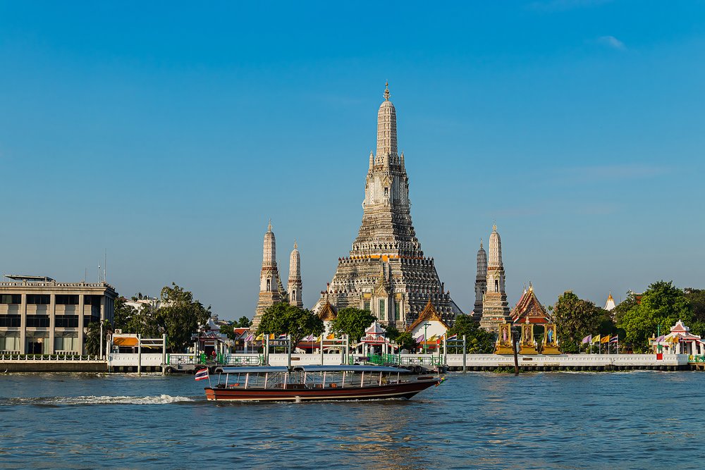Wat Arun temple seen from across the Chao Phraya River with a boat in the foreground