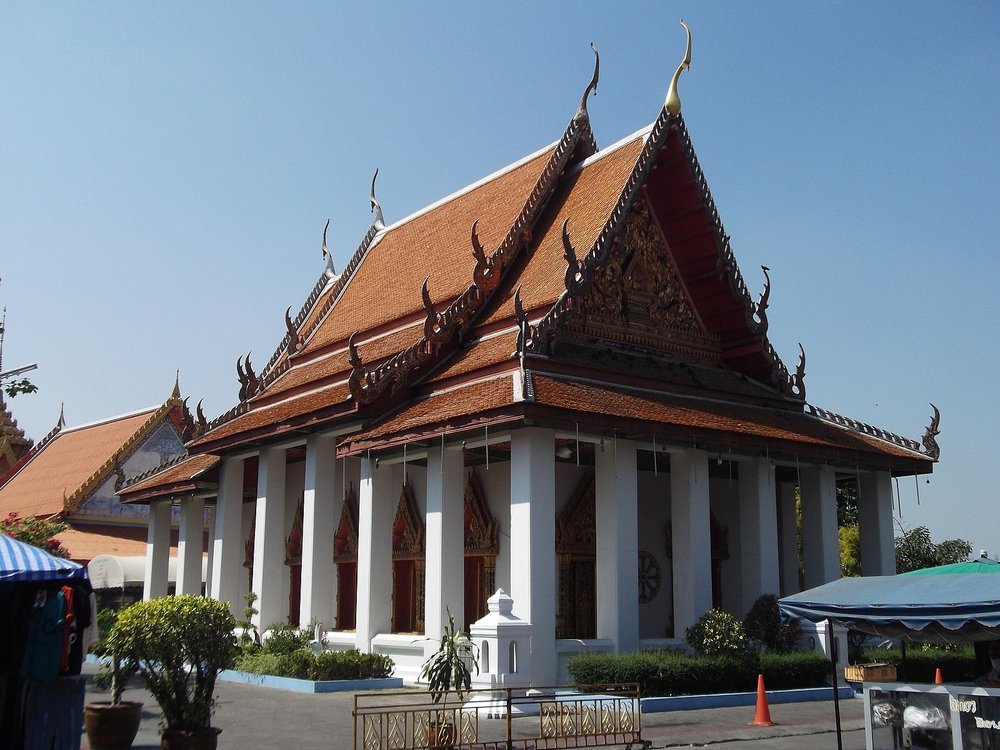 Traditional Thai temple building of Wat Mahabut with orange roofs and white pillars