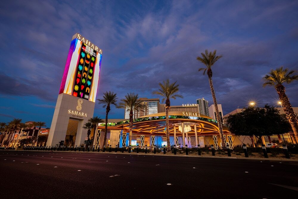 Night view of Sahara Las Vegas hotel with colorful lights and palm trees