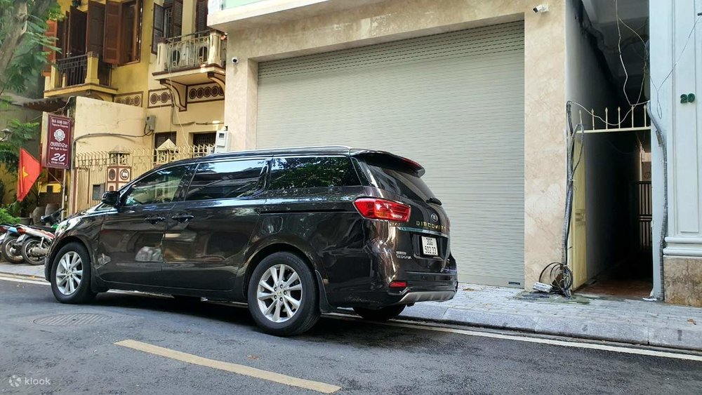 A black private car parked on the side of a narrow street