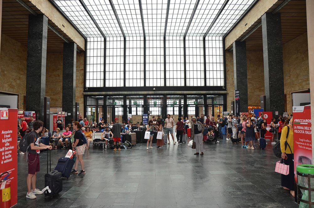 Busy interior of Florence SMN train station with travelers and ticket booths