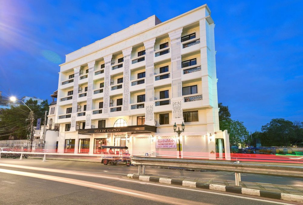 A street view of Villa De Khaosan, with a tuk-tuk in motion