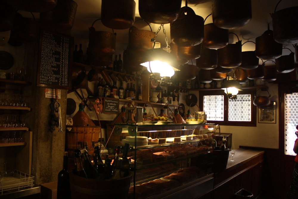 Interior of Cantina Do Mori with wine bottles and hanging copper pots