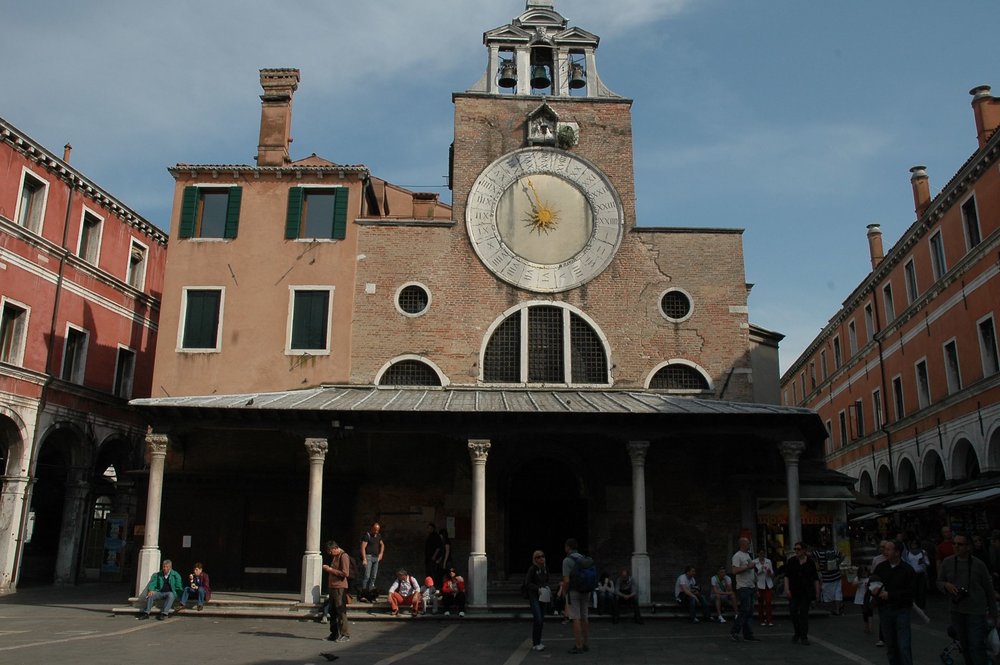 Exterior of San Giacomo di Rialto Church with large clock and visitors outside