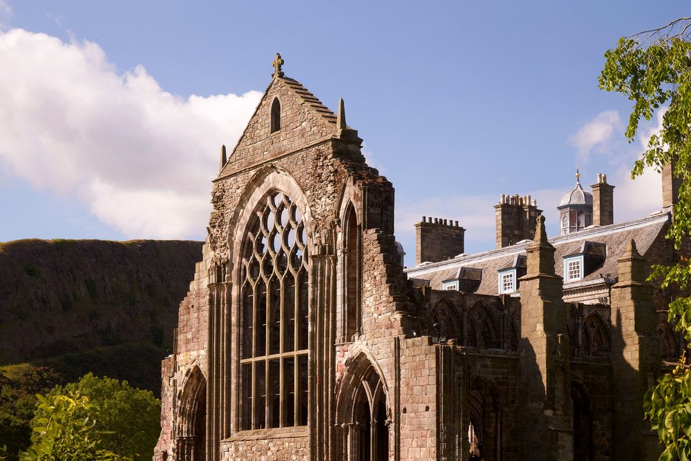 Stone ruins of Holyrood Abbey with gothic windows under a clear blue sky